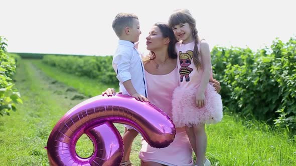 Happy Mother and Her Little Daughter and Son in the Summer Field alt