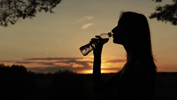 Silhouette of Young Woman Drinking Water
