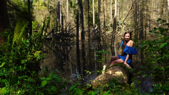 A Woman in a Blue Dress on the Background of Wild Nature