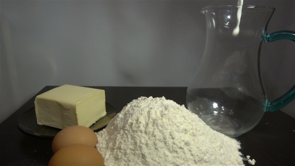 Wheat, Flour, Milk, Eggs and Butter on a Wooden Table