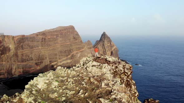 Man hiker in Red Jacket Walking on Cliff at Ponta de Sao Lourenco, Madeira island, Portugal