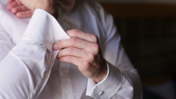 of a Hand of Groom Putting on Cufflinks. Wedding Preparations