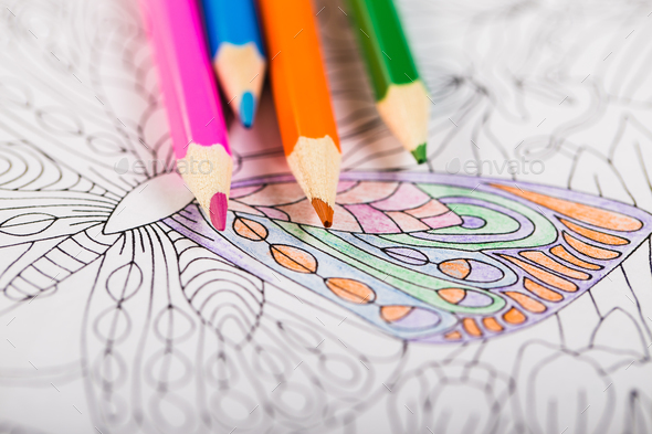 Multi-colored pencils and coloring book for adults - Stock Photo - Images