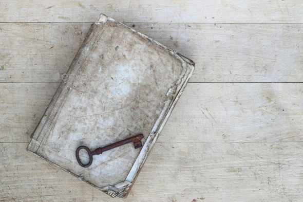 Old rusty key on torn book