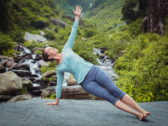 Woman doing yoga asana Vasisthasana - side plank pose outdoors