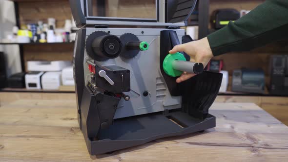 A Man Changes the Ribbon in an Industrial Label Printer