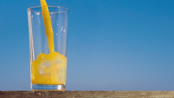 Pouring a Glass of Orange Juice Creating Splash
