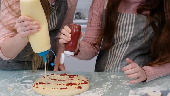 Close up hands of mother and daughter have fun with squeeze tomato sauce and mayonnaise