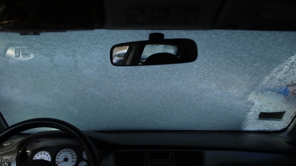 Young Woman Cleaning Car From Snow with a Brush alt