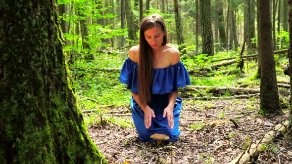 A Woman in a Blue Dress Found a Big Mushroom Among Wild Forest. Mystical Mood.