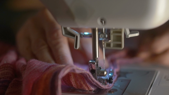 Hands Pushing Textile Through Sewing Machine in .