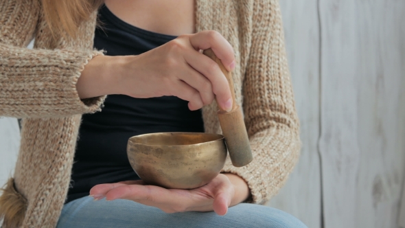 Young Woman in Cardigan Relaxing with Nepal Singing Bowl