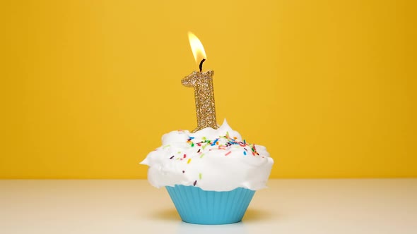 Birthday Cupcake With Burning Golden Candle Number One on Bright Yellow Background