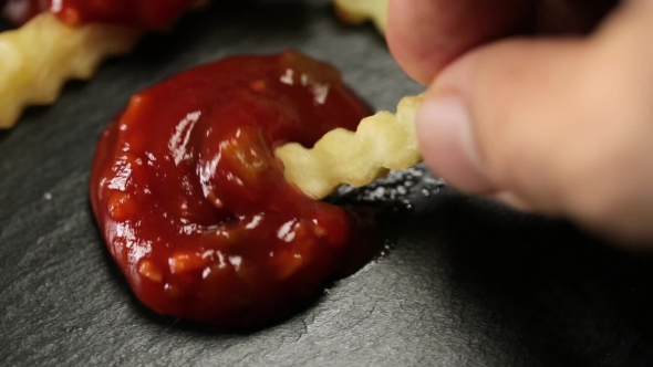 Man Dunks French Fries in Ketchup