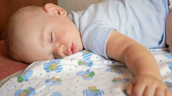 Beautiful Baby Sleeping in Funny Pose on a Bed
