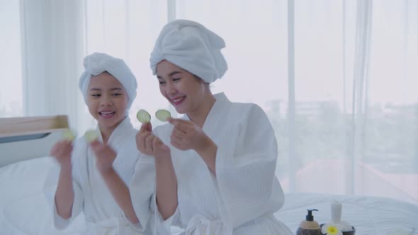 Spa concept. Mom and daughter are having fun with cucumber facials. 4k Resolution. alt