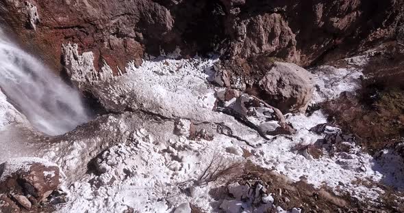 Roaring waterfall flow in winter splash cold water and ice around on snow covered ground in frozen i alt