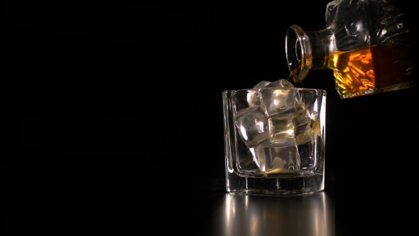 Whiskey on the Rocks Poured From a Rystal Decanter on Black Backround Copy Space