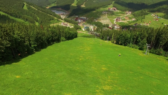 Aerial Flight Ski Slope in Summer. Drone Flying Over Mountain Forests and Village