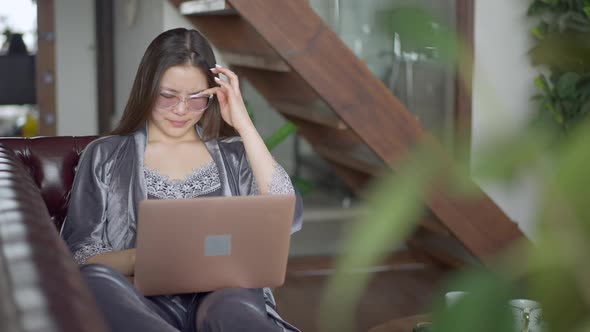 Portrait of Young Overworking Asian Woman Rubbing Eyes Closing Laptop and Stretching Smiling alt