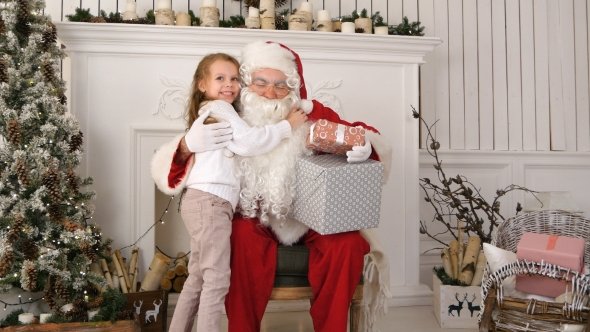 Santa Claus Holding Presents and Hugging a Little Cute Girl alt