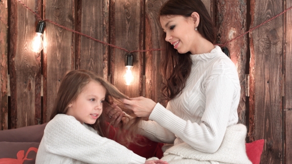 Happy Mother Combing Her Daughter's Hair While She Is Singing Christmas Song alt