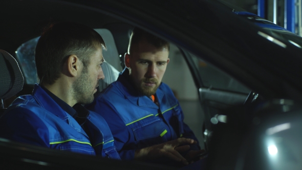 Two Auto Mechanic Diagnose Car Mechanics Sitting Inside the Car