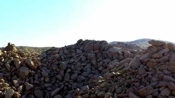 Drone shot flying towards some large rocks in the desert of Pioneertown, California. alt