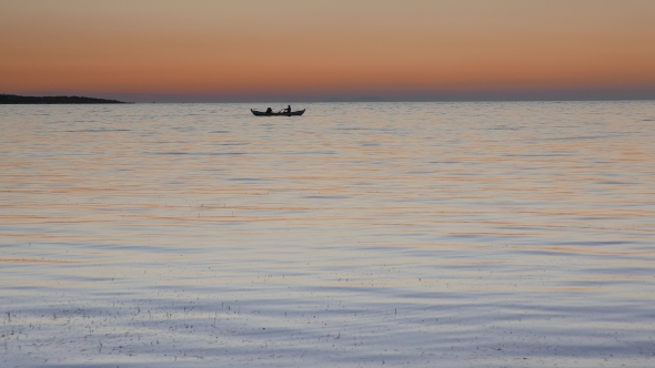 Calm Sea with a Rowing Boat with Two Fishermen at Sunset.