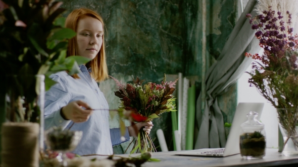 Ginger Florist Creating a Bunch of Flowers Near Laptop on Table