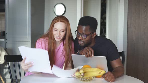 Interracial Couple Reading Mail and Checking Accounting at Home alt
