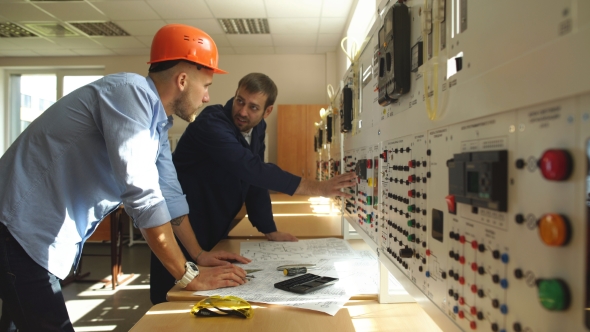 Young Engineer Taking Notes at Control Room in Factory