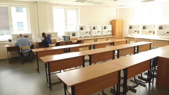 Rear View of Workers in the Control Room, Looking at Computer Monitor alt