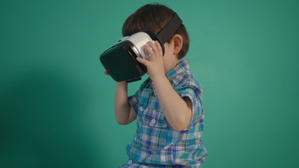 Little Boy Using Virtual Reality Device Over Green Wall