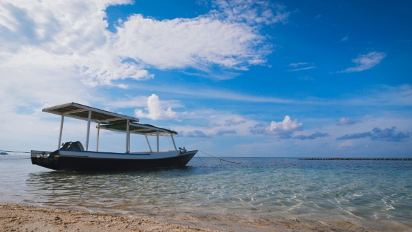 Small Boat with a Roof Standing Next To a Sandy Beach in the Open Ocean, Where There Are Small Waves alt