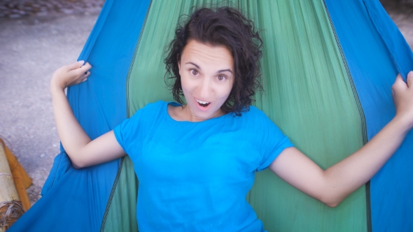 Young Cheerful Girl Lying in Hammock on Tropical Beach, Hiding Her Face and Laughing Happily alt