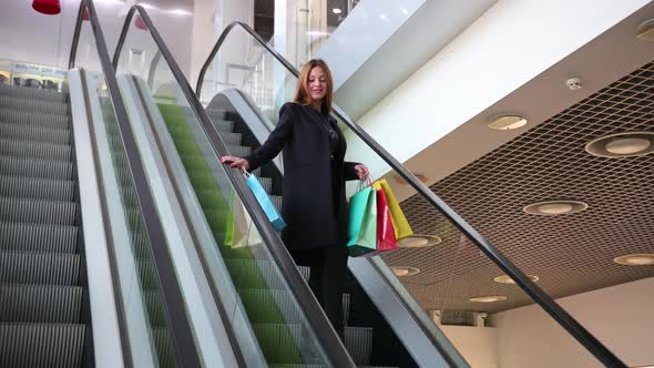 Young Woman Descends Going Down on an Escalator in Shopping Center alt