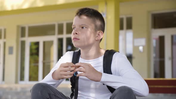 A Caucasian Teenage Boy Acts Frustrated As He Sits in Front of School  Closeup