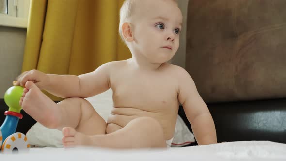 Caucasian Baby Boy Toy Sitting on Bed alt