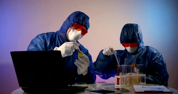 Two Virologist Dressed in Hazmat and Mask Respirators Are Working with Vaccine alt