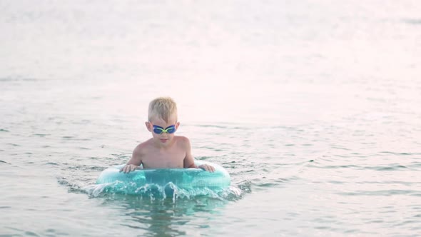Little Boy Comes Out of the Sea Ocean Water Child Having Fun Swimming on Blue Swimming Ring alt