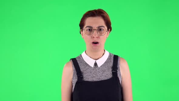 Portrait of Funny Girl in Round Glasses Is Scolding and Shaking Her Index Finger. Green Screen alt