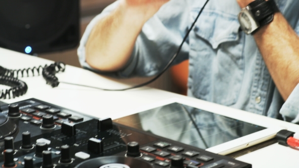 Disc Jockey's Face and Hands While He Changes Settings of the Sound Control System alt