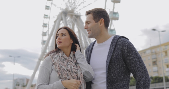 Young Couple Standing in Front of a Ferris Wheel alt