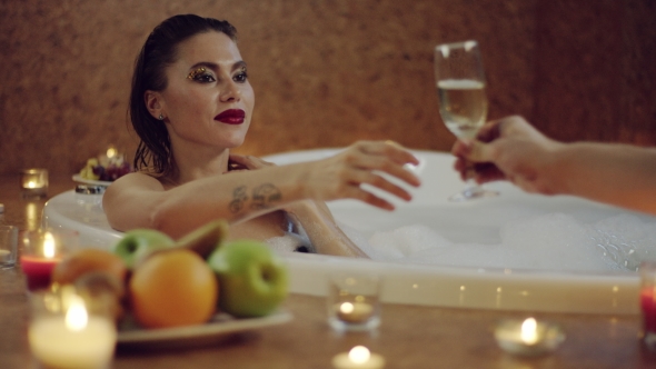 Beautiful Woman Taking a Glass of Champagne From Boyfriend in Bath