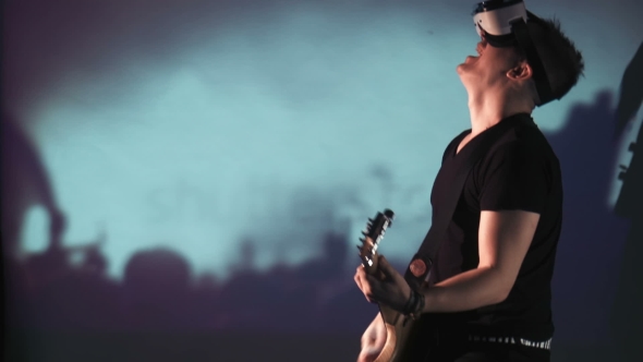 Man in VR Glasses Playing Guitar at Concert alt