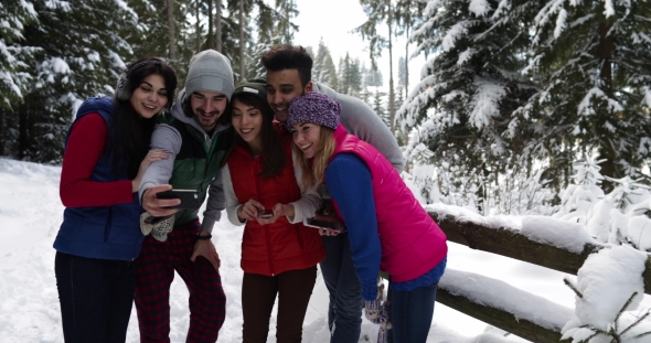 Group Of People Winter Snow Forest Smiling Friends Using Smart Phone Internet In Snowy Park