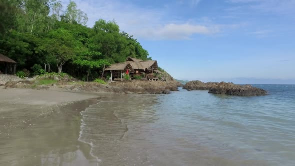 Sandy Beach With Rocks and Wooden Bungalow