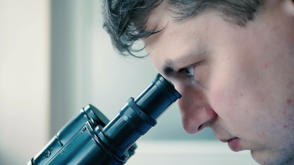 Lab Technician Looks Through a Microscope alt