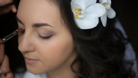 Woman Does Make Up for Bride with White Orchid in Her Black Hair